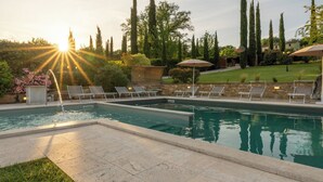 A rectangular swimming pool with a stone border, surrounded by lounge chairs and a stone wall. - La Colonica 18, Emma Villas (Citerna)