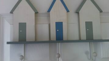 A wall-mounted shelf with three wooden houses, each with a door.