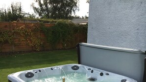 A hot tub with a champagne bottle and glasses, surrounded by a patio area with a stone floor. - Hot tub, beautifully restored Manse. Fantastic midweek rates available. (Stanley)