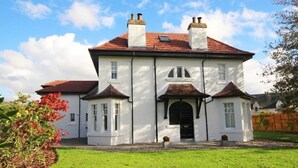A large, white, two-story house with a red-tiled roof and multiple chimneys. - Hot tub, beautifully restored Manse. Fantastic midweek rates available. (Stanley)