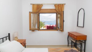 A bedroom with a bed, a nightstand, a desk, a window with curtains, and a mirror. - Detached Villa with Panoramic Sea Views in Beautiful Vlicha Bay, Lindos, Rhodes (Rhodes Island)