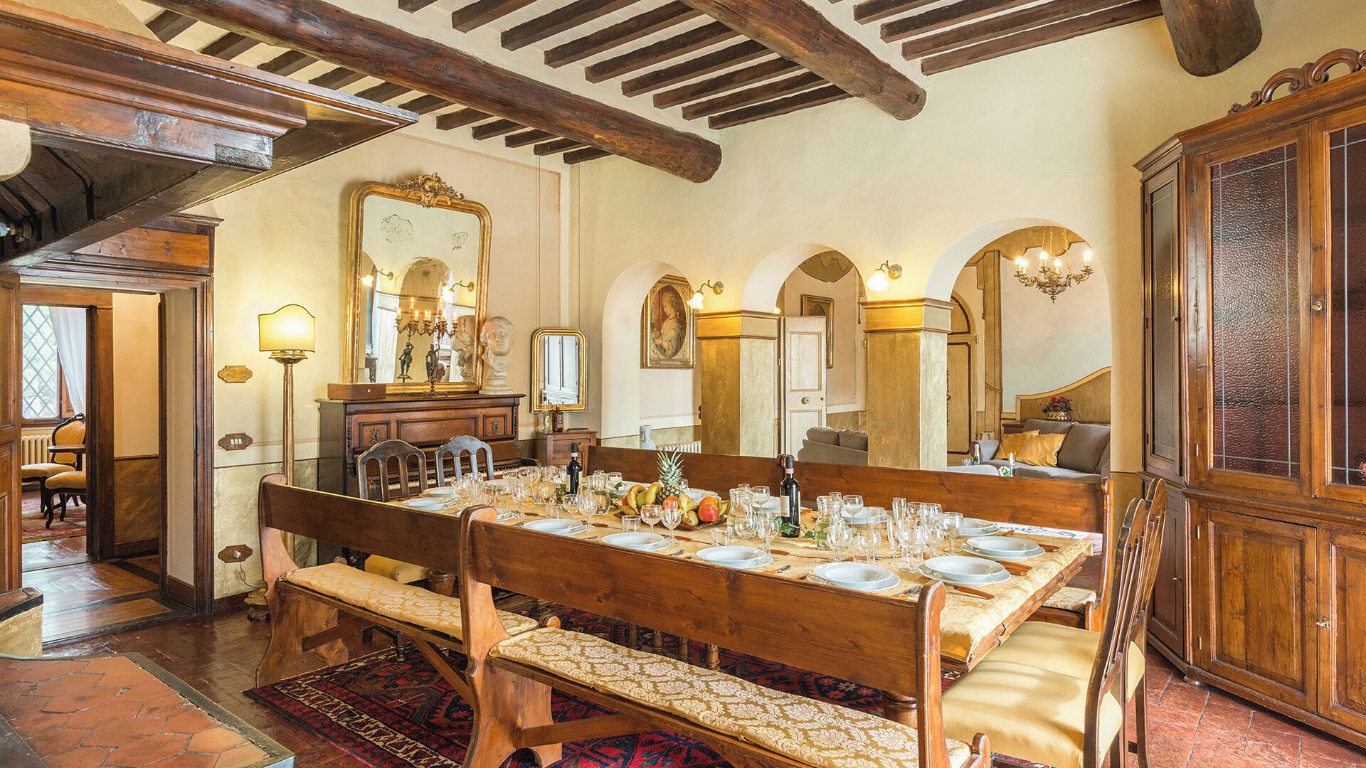 A dining room with a wooden table set for a meal, flanked by chairs and benches.