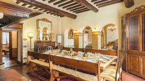 Une salle à manger avec une table en bois dressée pour le repas, entourée de chaises et de bancs.