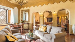 Un salon spacieux doté d’une cheminée, de sièges confortables et d’un coin repas visible à travers une arche.