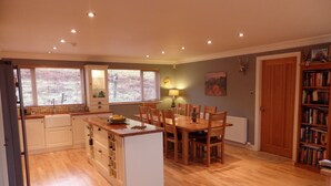 Une cuisine spacieuse dotée de meubles en bois, d’un îlot central et d’un coin repas avec des chaises.