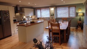 Une cuisine moderne avec des meubles en bois, un îlot central et un coin repas doté de chaises en bois.