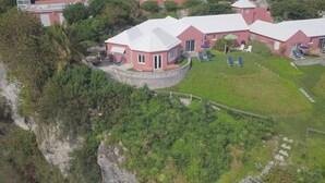 Une propriété située sur la côte, comprenant un bâtiment circulaire, une pelouse et un mur de soutènement en pierre.