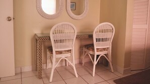Une pièce comprenant deux fauteuils en osier blancs, une petite table et deux miroirs fixés au mur.