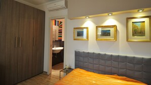 A bedroom with a bed, a wardrobe, a bathroom, and framed pictures on the wall. - Elegant house with veranda - in the center of Rome, a stone's throw from S. Giovanni  (Roma)