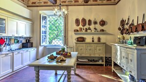 Una cocina tradicional con armarios blancos, una mesa de madera y una variedad de utensilios de cocina y batería de cocina exhibidos en las paredes.