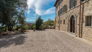 Un edificio de piedra con un patio de grava, ventanas de arco y vistas al mar.