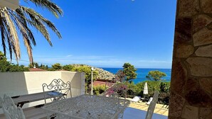 Un patio con tavolo e sedie in metallo bianco, con vista sulla costa.