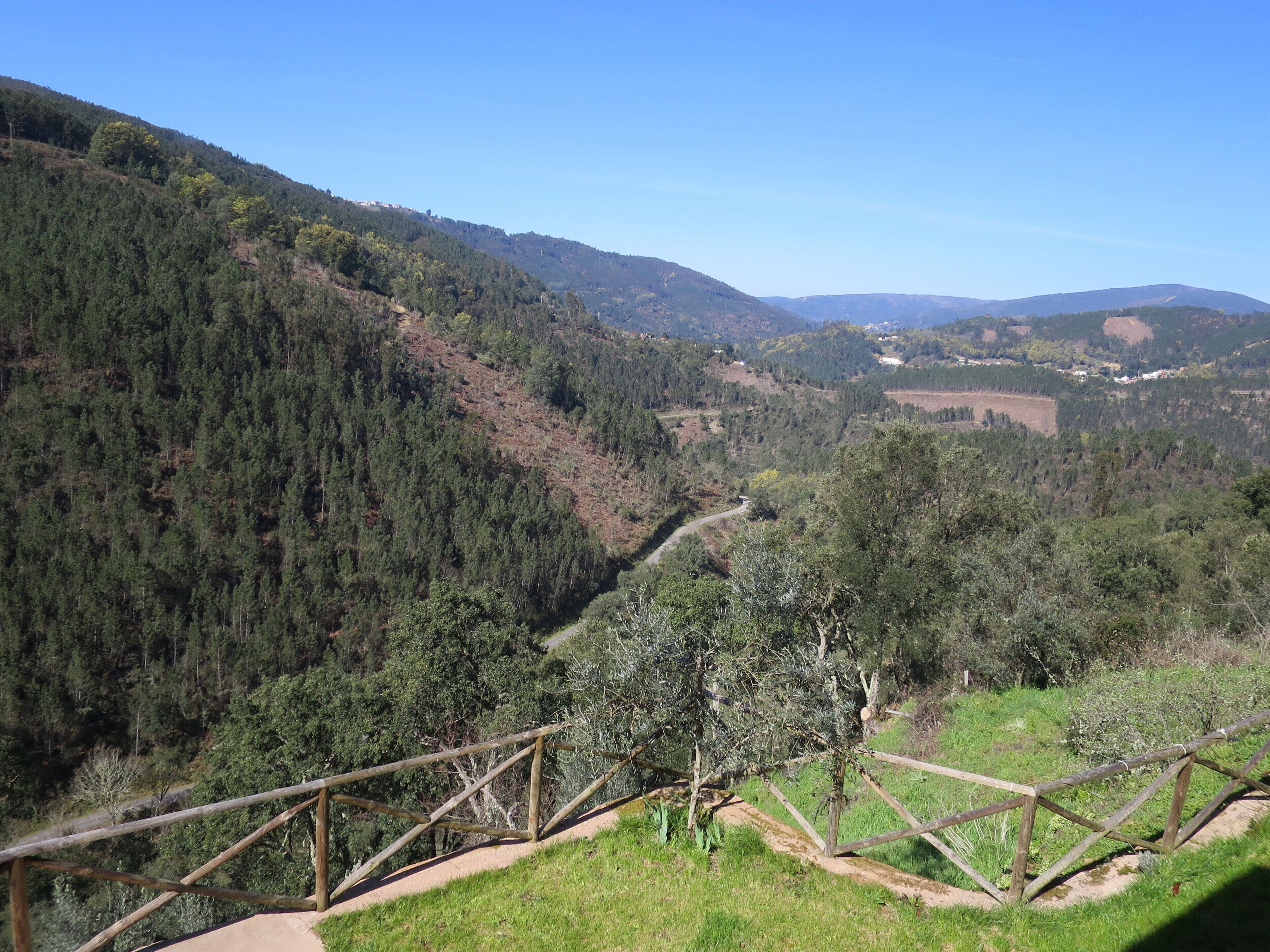 Un paysage montagneux avec un sentier de terre et une clôture en bois.