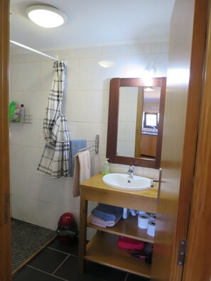 A bathroom with a white sink, a mirror, a towel rack, and a shower curtain.