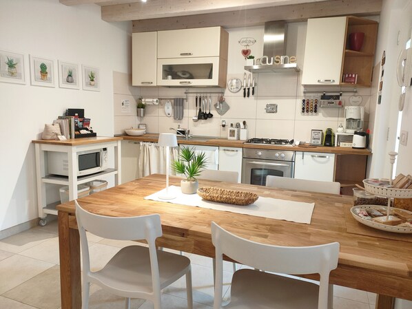 Une cuisine moderne avec des meubles blancs, une table à manger en bois et une plante en pot.