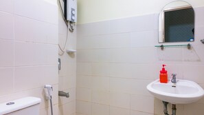 A bathroom with white tiles, a toilet, a sink, and a shower. - San Remo Oasis Serviced Apartments (Cebu City)