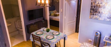 A compact living space with a dining area, a television, and a small kitchenette.
