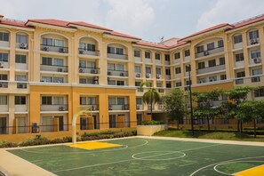 A multi-story hotel with balconies, a basketball court, and a landscaped garden. - San Remo Oasis Serviced Apartments (Cebu City)