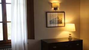 Una habitación con un aparador de madera, un cuadro en la pared y una lámpara que ilumina.
