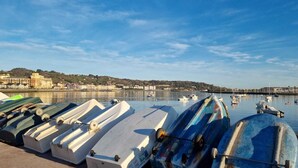Een jachthaven met meerdere boten afgemeerd, een rustig wateroppervlak en een stadsgezicht op de achtergrond.