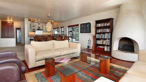 A spacious living room with a sofa, coffee table, and fireplace. - Private villa in Gordons Bay with ocean views and pool (Cape Town)