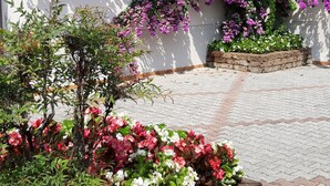 A building with a white exterior, wooden shutters, and a wooden planter box with flowers. - Lovely apartment on Lake Garda in residence with pool (San Felice del Benaco)