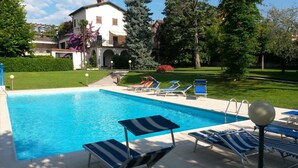 A swimming pool with lounge chairs and a house in the background. - Lovely apartment on Lake Garda in residence with pool (San Felice del Benaco)