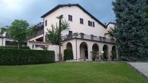 A two-story building with a balcony, arched entrance, and a well-maintained lawn. - Lovely apartment on Lake Garda in residence with pool (San Felice del Benaco)