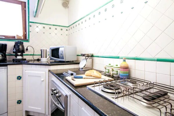 A kitchen with a gas stove, a toaster, a coffee maker, and various kitchen items on the counter.