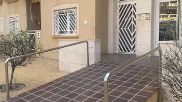 Un edificio de varios pisos con una rampa de acceso, barandales metálicos y una planta baja con azulejos.
