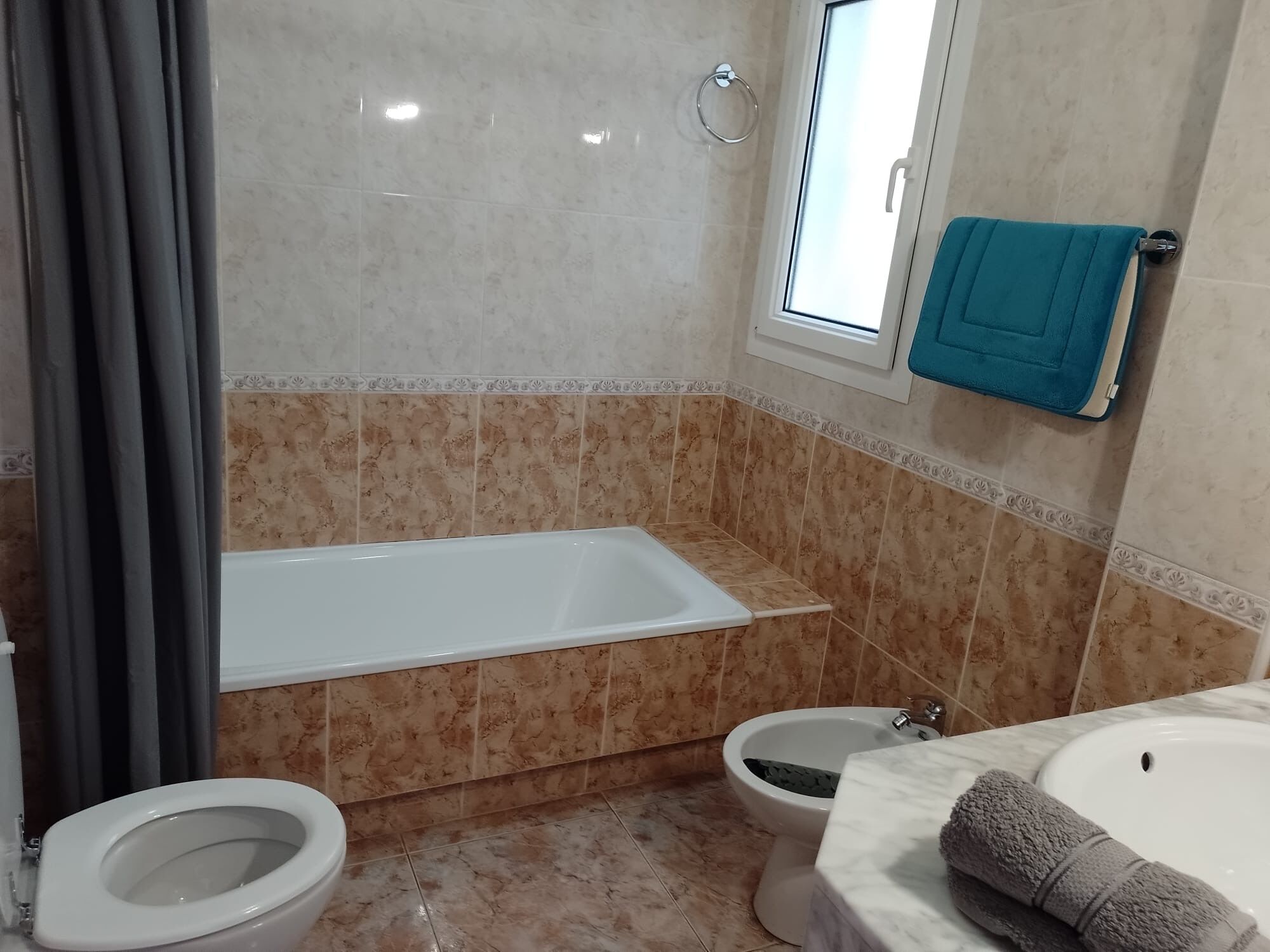 A bathroom with a bathtub, two toilets, a bidet, and a sink.