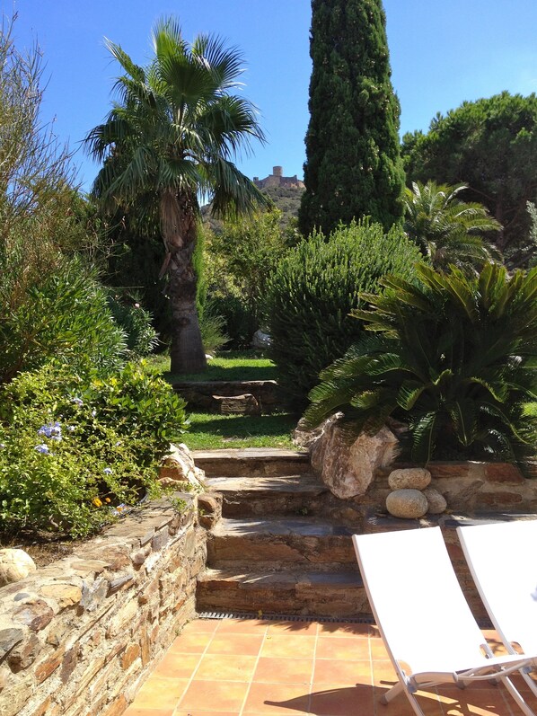 Un giardino con gradini in pietra che conducono a una zona relax bianca.