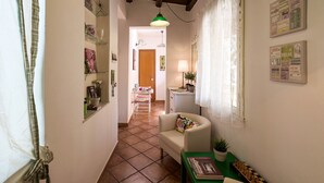 A narrow hallway with a tiled floor, a white sofa, a green table with a chessboard, and a small plant. - Finocchiaro Penthouse - Terrace in the Center WiFi Free (Palermo)