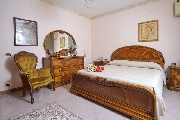 A bedroom with a large bed, a wooden dresser, a chair, and a mirror. - EXCLUSIVE - 20 min Rome, few min from the sea, villa with private pool (Ladispoli)
