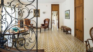 A spacious room with a patterned floor, a wooden door, and a dining area with chairs and a table. - Villa with pool and stunning views, 22 sleeps! (Trecastagni)
