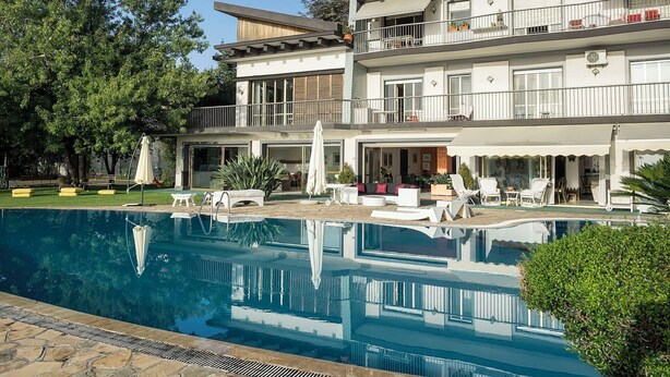 A modern two-story building with a swimming pool, outdoor seating, and a wooden deck. - Villa with pool and stunning views, 22 sleeps! (Trecastagni)