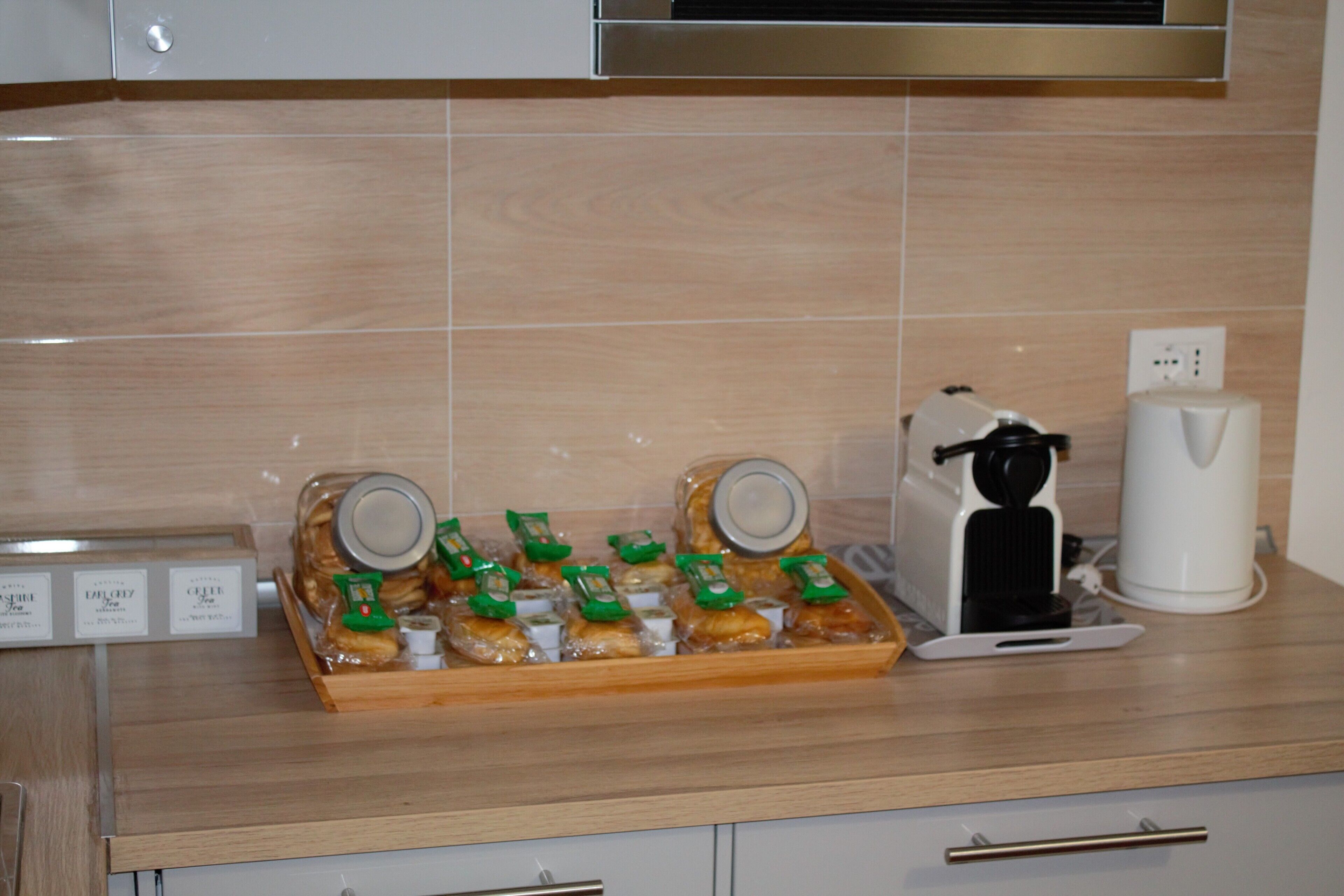 A kitchen counter with a tray of packaged snacks, a coffee maker, and a kettle.