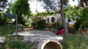 A garden with a gravel path, various plants, and a large, empty concrete planter. - LA CASA DE LÚ, POOL, BBQ GARDEN, FREE WIFI, 30MIN BEACH IN CENTRO ANDALUCíA (Archidona)
