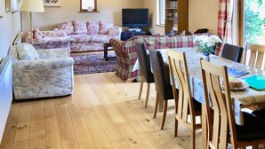 A cozy living room with a sofa, a television, and a dining area with a table and chairs.