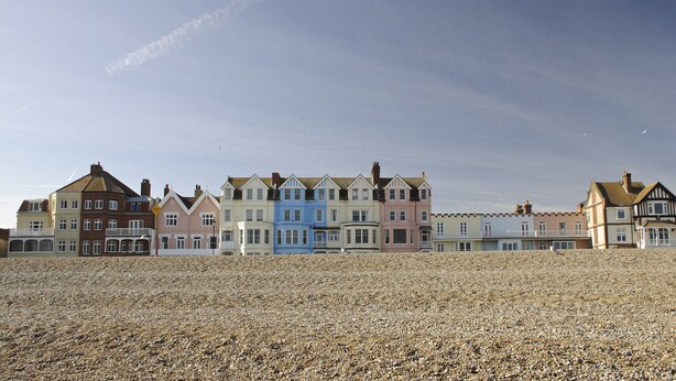 A row of colorful seaside houses with a pebbled beach in the foreground.