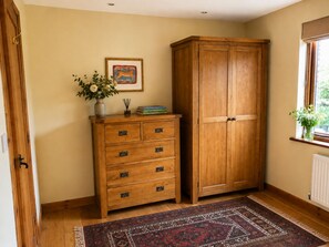Une pièce avec un meuble en bois, un tapis à motifs et un tableau encadré accroché au mur.