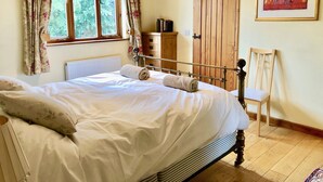 A bedroom with a bed, a chair, a wooden wardrobe, a radiator, and a window with curtains.