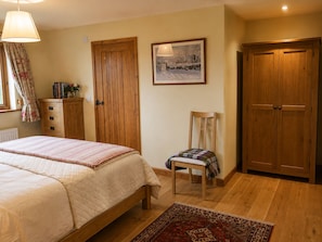 A bedroom with a bed, a chair, a wardrobe, a radiator, and a painting on the wall.
