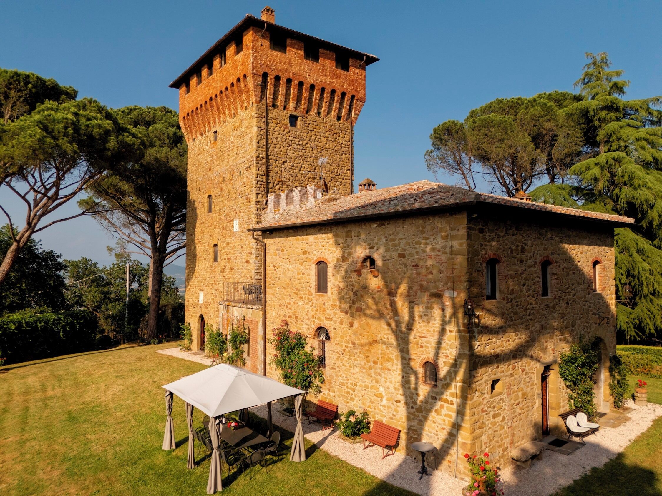 A stone building with a tower, a covered patio, and outdoor seating.