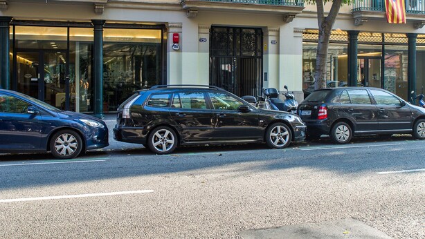 Ein mehrstöckiges Gebäude mit Balkonen, einem Baum davor und geparkten Autos.