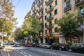 Ein mehrstöckiges Gebäude mit Balkonen, parkenden Autos und Bäumen entlang der Straße.