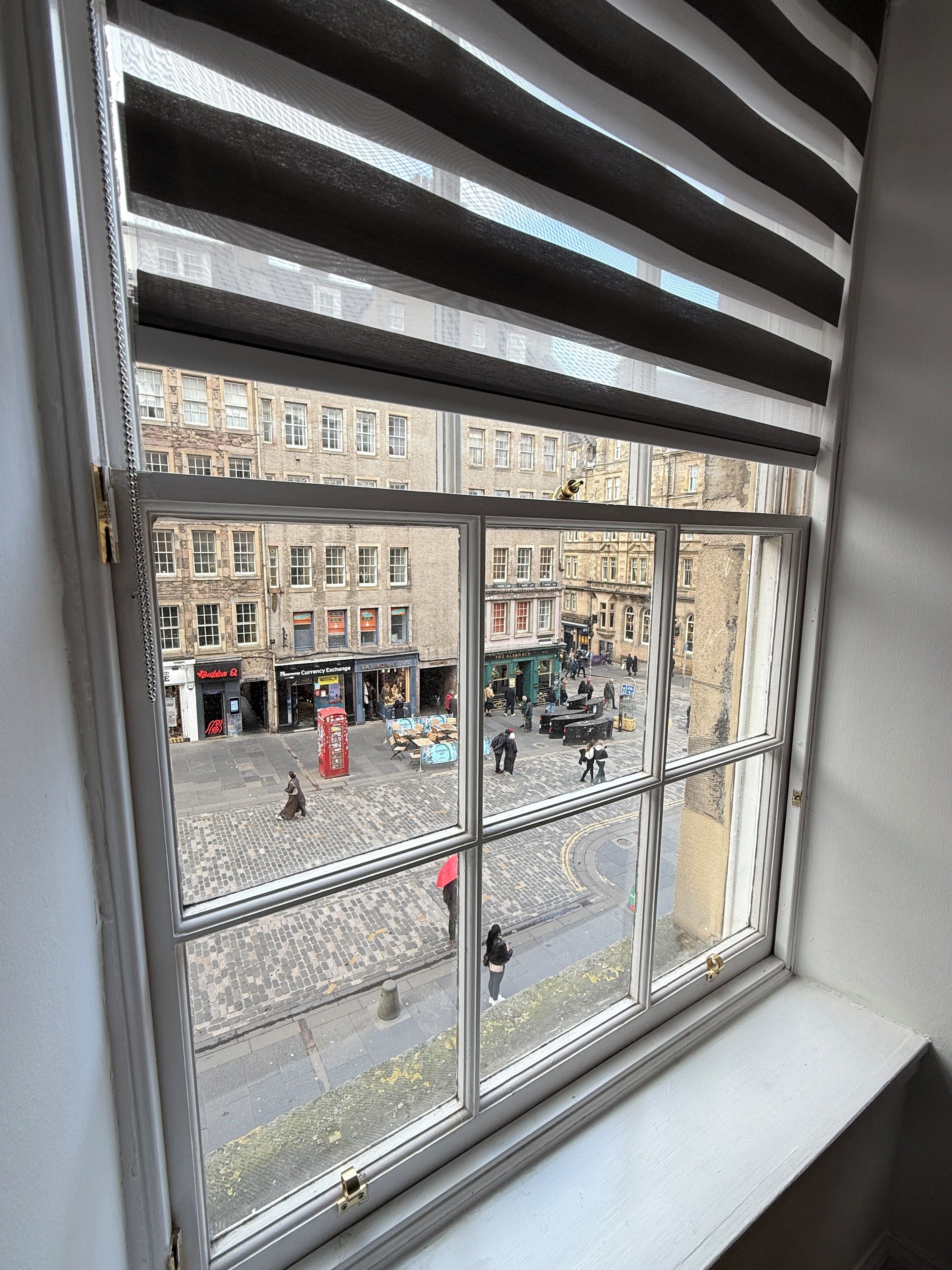 Una ventana con vistas a una calle, con edificios y un teléfono rojo.