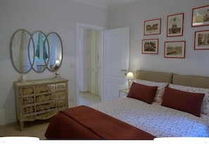 Un dormitorio con cama, cómoda, espejo y cuadros en la pared.