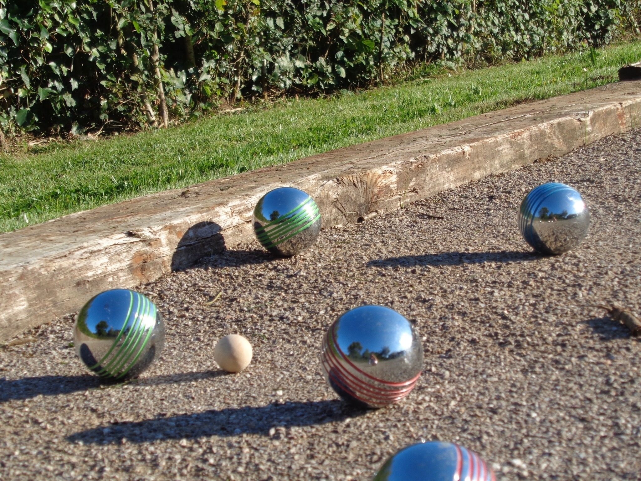 A gravel path with several reflective spheres and a log.