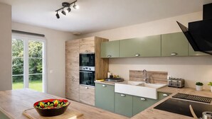 A modern kitchen with a large window, built-in oven, and a sink.